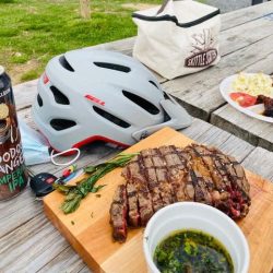 Biking helmet on a table next to a freshly cooked steak